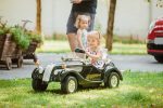 The little baby girl playing at car against green grass